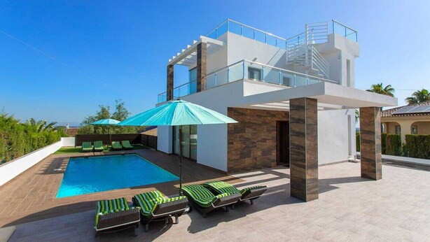 Una casa moderna con piscina, area relax esterna e scala in vetro.