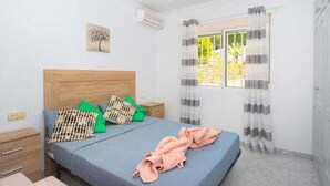 A bedroom with a bed, a nightstand, a window with curtains, and a ceiling fan.