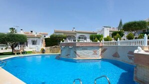 A swimming pool with a stone border and metal ladders.