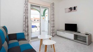 A modern living room with a sofa, a TV, and a small table.