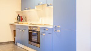 Eine moderne Küche mit blauen Schränken, einem eingebauten Backofen und einer Arbeitsplatte mit Kaffeemaschine.