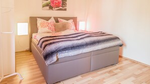 Ein modernes Schlafzimmer mit Bett, Kopfteil, Nachttisch und einem Wandbild.