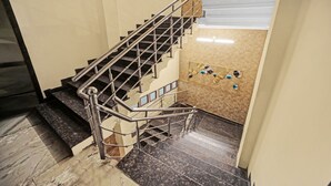 A staircase with a metal railing, marble steps, and a wall with decorative shells. - The Bagga Inn (Jabalpur)