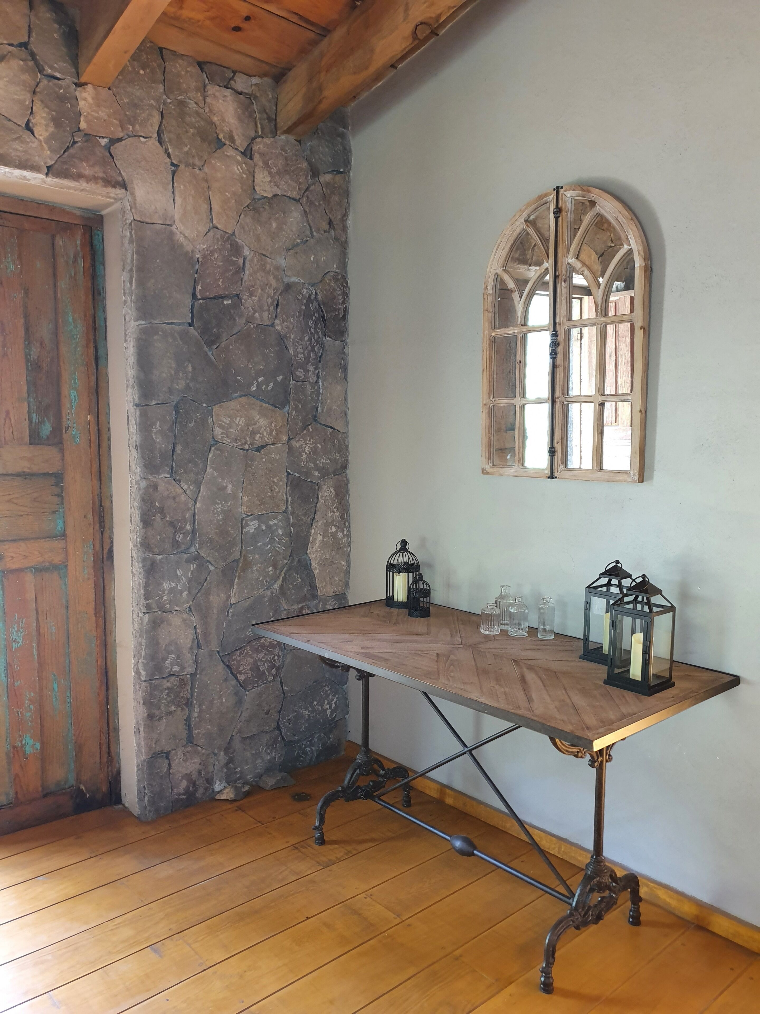 Une pièce rustique avec un mur en pierre, une porte en bois et une table décorée de lanternes.