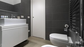 Een moderne badkamer met een wit wastafelmeubel, spiegel en toilet.