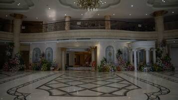 A grand lobby with a large marble floor, a chandelier, and a balcony with railings.