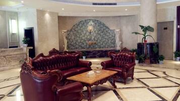 Un hall con piso de mármol, dos sillones de cuero, una mesa de centro de madera y una pared decorativa con un emblema central.