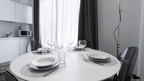 A dining table set with plates, glasses, and cutlery, with a microwave and cabinets in the background. - Italianway Collection - Corso Como 11 - C (Milan)