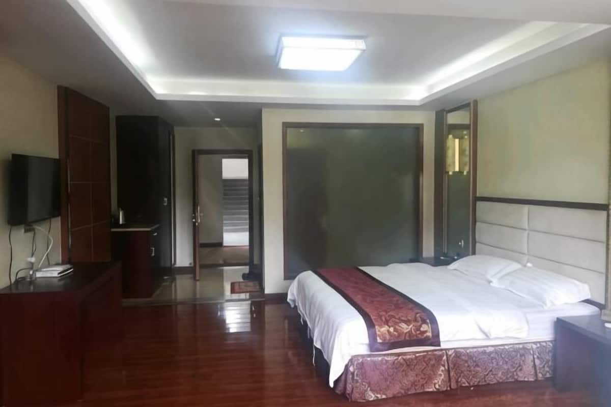 A hotel room with a bed, a desk, a television, and a wardrobe.