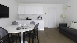 Ett modernt och kompakt bostadsutrymme med matplats, pentry och en soffa.