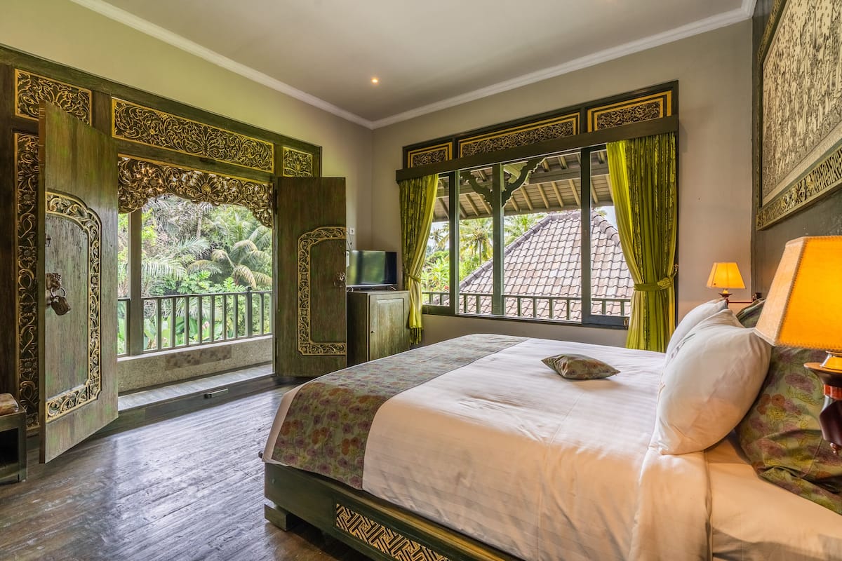 A bedroom with a bed, a TV, and a window with curtains.