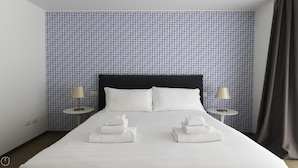 A neatly made bed with white linens, two bedside lamps, and a patterned wallpaper. - Italianway Collection - Corso Como 11 - F (Milan)