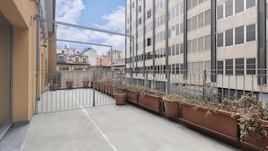 A balcony with a metal gate, potted plants, and a view of surrounding buildings. - Italianway Collection - Corso Como 11 - F (Milan)