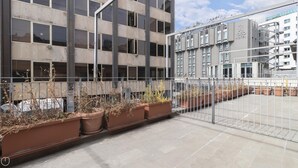 A modern building with multiple floors, large windows, and a gated outdoor area with potted plants. - Italianway - Corso Como 11 - 7 (Milan)