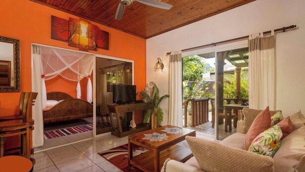 A room with a bed, a TV, a coffee table, and a sofa. - Effi Mountain View Colibri Villa (Mahé Island)