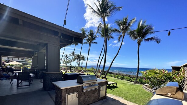 An outdoor patio with a grill, seating, and a view of the ocean. - Ekahi 27A: Priceless Ocean View from a Private Lanai (Kihei)