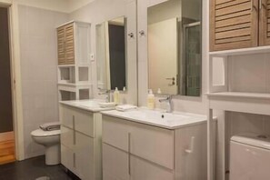 Une salle de bain moderne avec deux lavabos, des toilettes et un grand miroir.