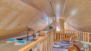 An attic room with a sloped ceiling, wooden beams, a small wooden staircase, a globe, and a metal mesh screen. - Vineyard Cottage Vesna Lake View (Cirkulane)