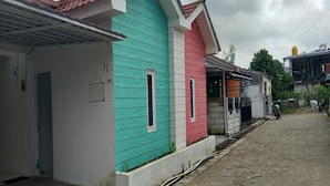 A row of colorful houses with a dirt road in front. - OYO 90974 Homestay Golo Koe Sejahtera (Labuan Bajo)