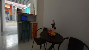 A small room with a desk, a chair, a table, and a TV. - OYO 90974 Homestay Golo Koe Sejahtera (Labuan Bajo)