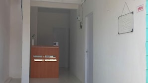 A reception area with a wooden desk, a whiteboard with notes, and a sign indicating the space is open. - OYO 90974 Homestay Golo Koe Sejahtera (Labuan Bajo)