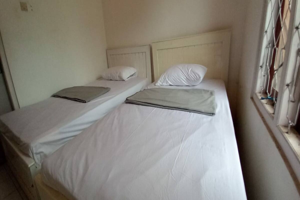 A room with two single beds, each with a headboard and pillows.