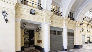 A grand entrance with a tiled floor, large columns, and a closed shutter door. - Piazza Nicola Amore 14 (Naples)