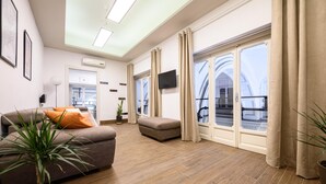 A spacious living room with a sofa, ottoman, and potted plants. - Piazza Nicola Amore 14 (Naples)
