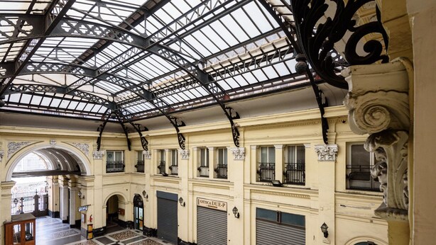 An indoor atrium with a high ceiling, patterned floor, and multiple closed shutters on the walls. - Piazza Nicola Amore 14 (Naples)