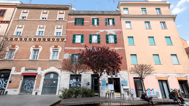 A street with buildings, a tree, and a bench. - La Pietra al Pigneto (Rome)