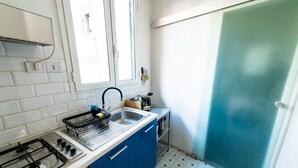 A compact kitchen with a gas stove, a sink, and a blue cabinet. - La Pietra al Pigneto (Rome)