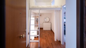 A bedroom with a bunk bed, a small white dresser, a round mirror, and a door leading to another room. - La Pietra al Pigneto (Rome)