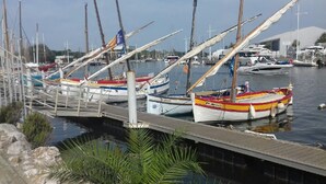 A marina with several boats docked, a wooden dock, and a clear sky.