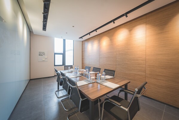 Un salón de conferencias con una mesa larga, sillas y una pared de madera decorativa.