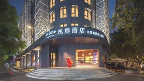 A modern hotel with a curved facade, illuminated windows, and a prominent entrance with steps. - UrCove by Hyatt Nanjing Downtown (Nanjing)