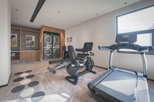 Un gimnasio moderno en casa con cinta de correr, elíptica y mancuernas.