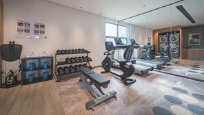 A modern gym with exercise equipment, dumbbells, and water bottles. - UrCove by Hyatt Nanjing Downtown (Nanjing)