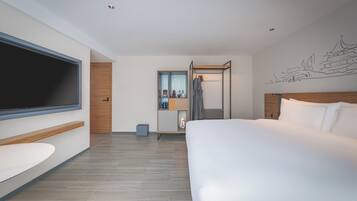 Una habitación de hotel moderna con una cama grande, televisión, armario y baño.