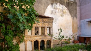 Une cour extérieure avec un bâtiment doté de fenêtres en arc de cercle et d’une façade en pierre.