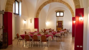 Un espace repas comprenant plusieurs tables et chaises, des plafonds en arc de cercle et un mur d’accent de couleur rouge.