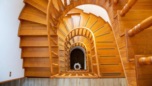 Un escalier en colimaçon en bois doté d’un mécanisme d’engrenage décoratif central.