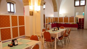 Un espace repas avec des tables et des chaises, un buffet et un sol carrelé.