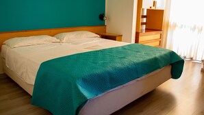 Un lit bien fait, recouvert d’une couvre-lit à motifs turquoise, avec une tête de lit en bois et un plancher en bois.