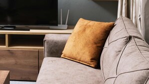 Un salon moderne doté d’un téléviseur à écran plat, d’étagères en bois et d’un canapé agrémenté de coussins.