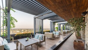 An outdoor seating area with tables and chairs, a wooden ceiling, and a view of the city. - Siddhartha Vilasa (Siddharthanagar)