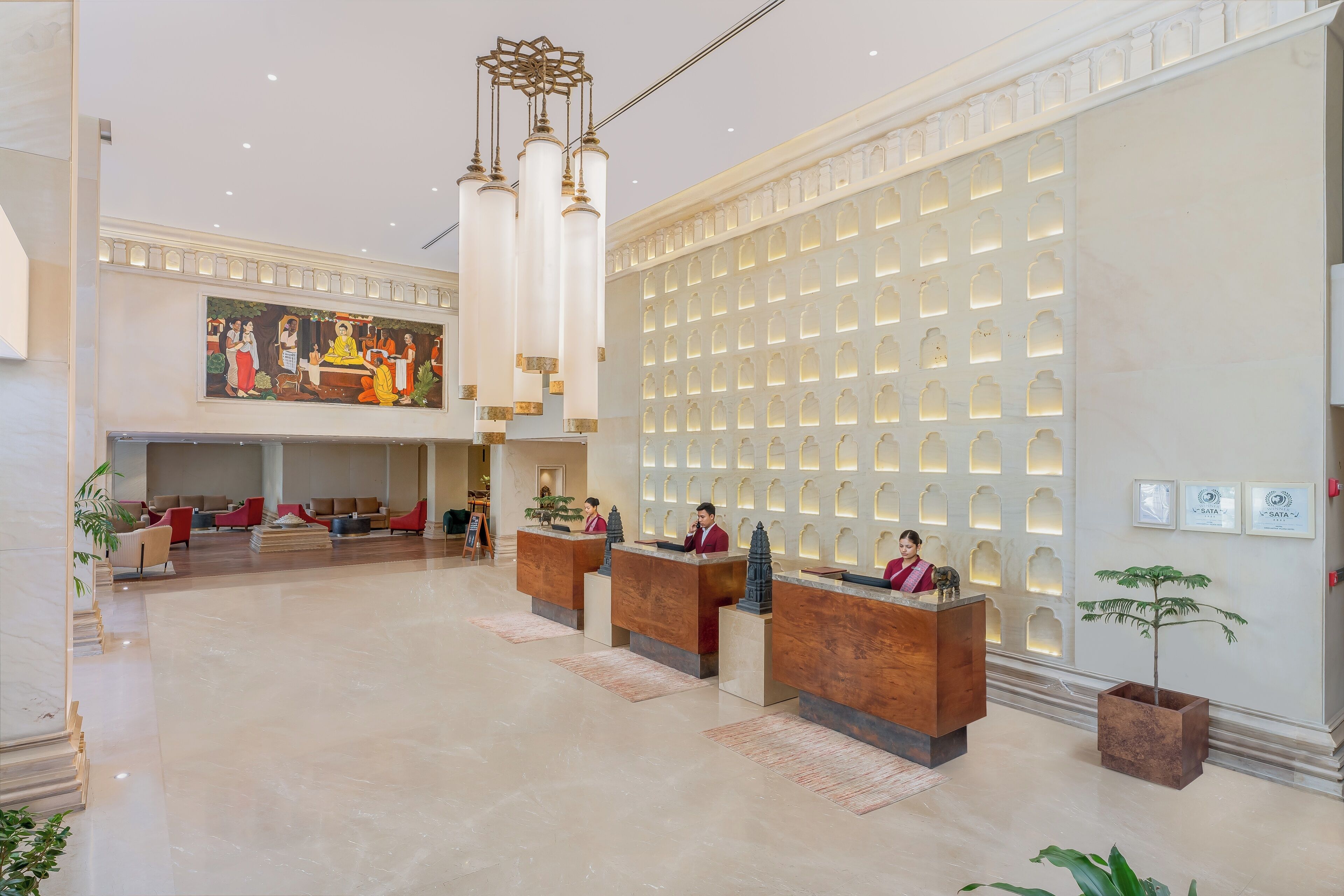 A hotel lobby with a reception desk, seating area, and a large mural.