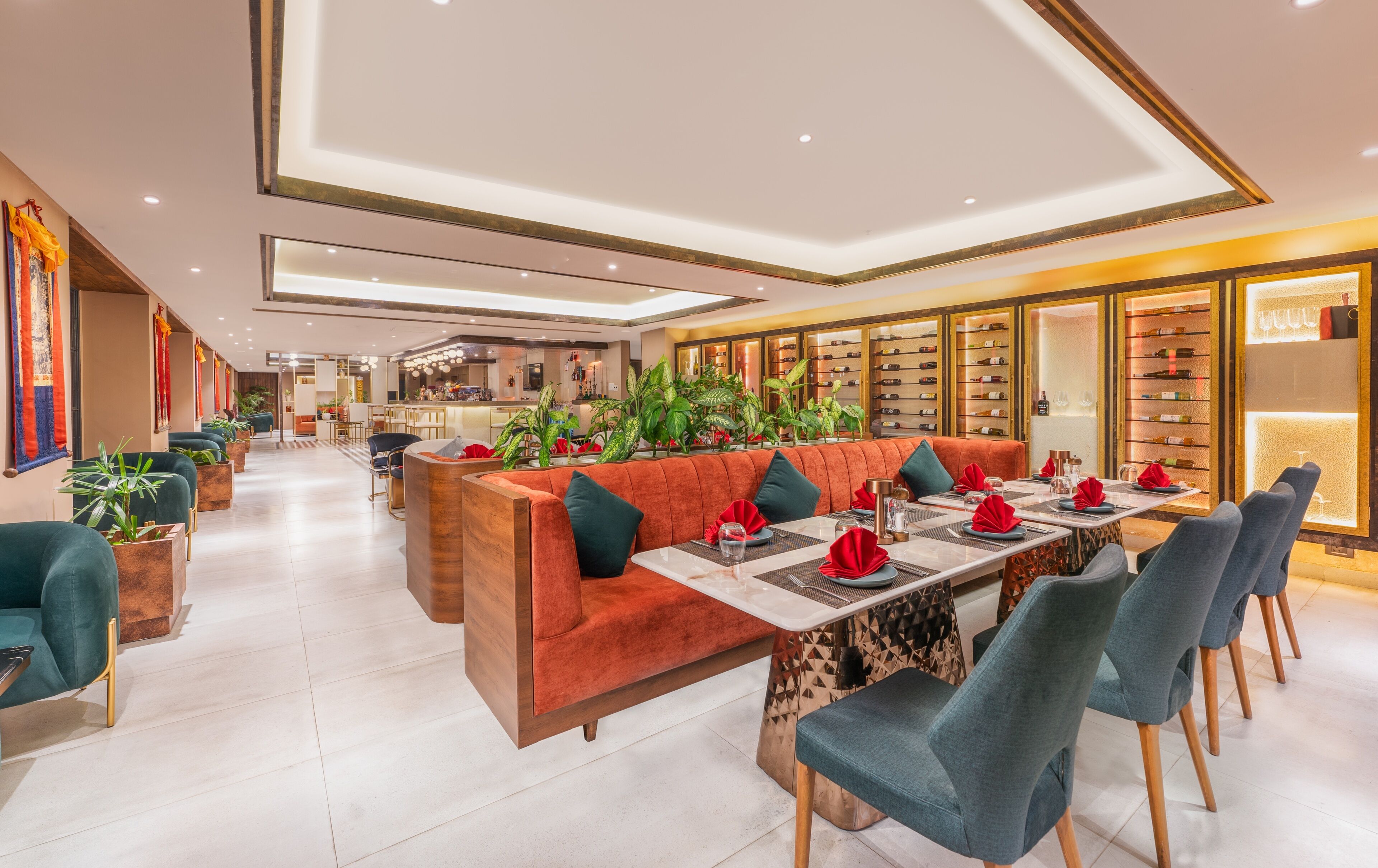 A modern dining area with a long table, cushioned seating, and a bar in the background.