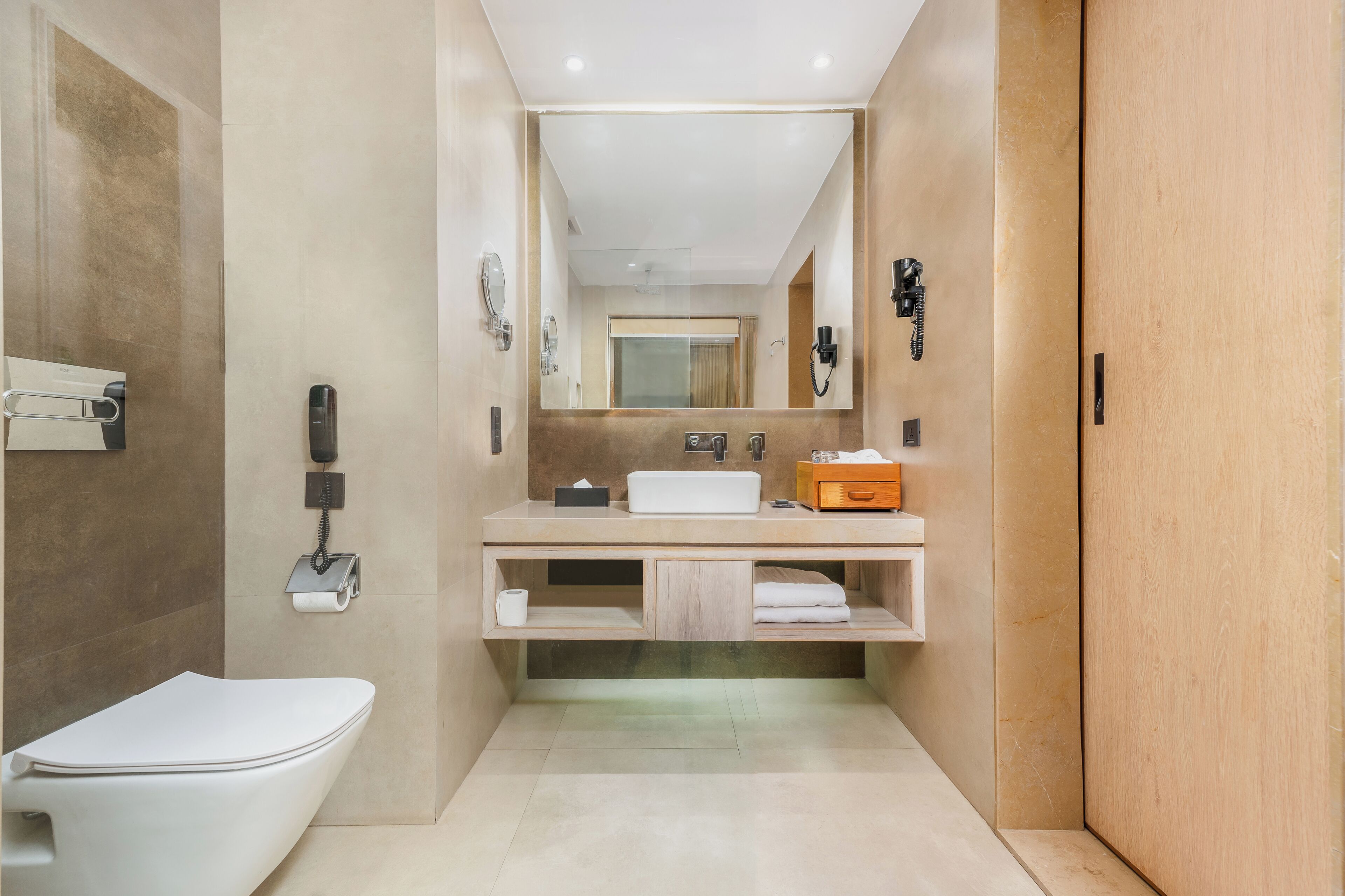 A modern bathroom with a toilet, sink, mirror, and towel rack.
