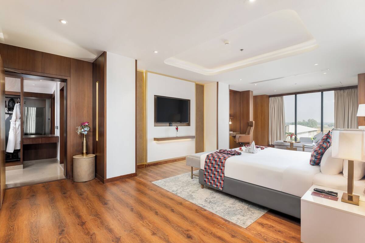 Een moderne hotelkamer met een groot bed, een televisie, een bureau en uitzicht op het omliggende landschap.