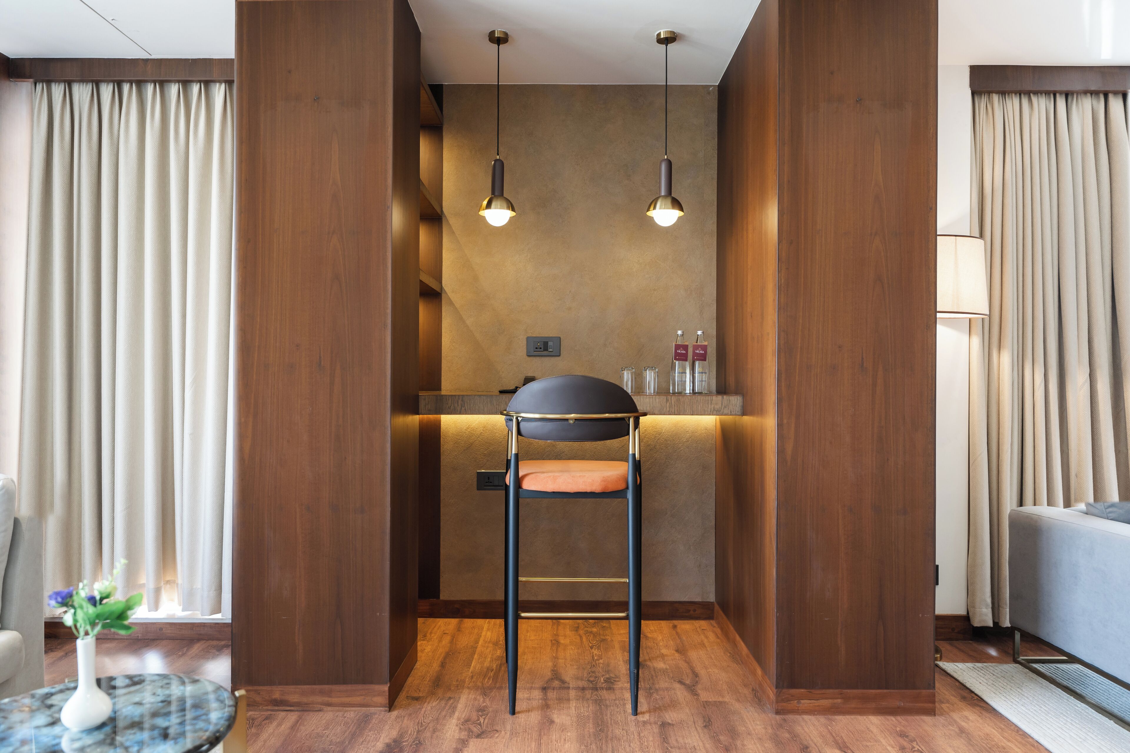 A modern room with a wooden accent wall, a bar area, and a seating area with a chair.